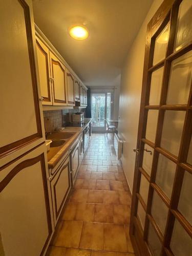 une cuisine avec un long couloir menant à une chambre dans l'établissement F2 avec Terrasse, Parking gratuit, à Guyancourt