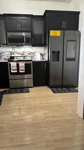 a kitchen with black cabinets and stainless steel appliances at Villas in A Gated Community in May Pen