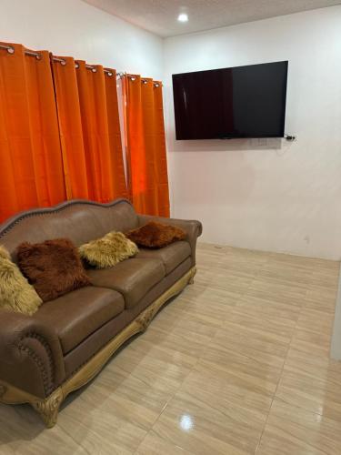 Sofá marrón en una habitación con cortinas naranjas en Villas in A Gated Community, en May Pen