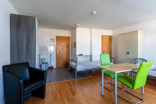 ein Wohnzimmer mit einem Tisch und grünen Stühlen in der Unterkunft Monteurapartment 5 in Rodgau
