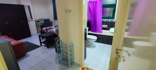 baño con aseo y cortina de ducha rosa en Cozy Bedroom for Gent, en Sharjah