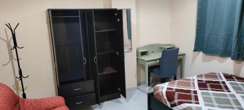 a bedroom with a black cabinet and a desk at Cozy Bedroom for Gent in Sharjah