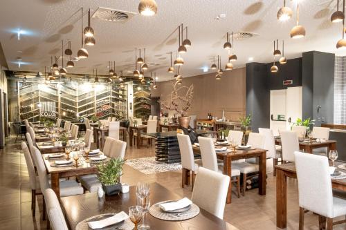 a restaurant with wooden tables and white chairs at MW Douro Wine & Spa in Santa Marta de Penaguião