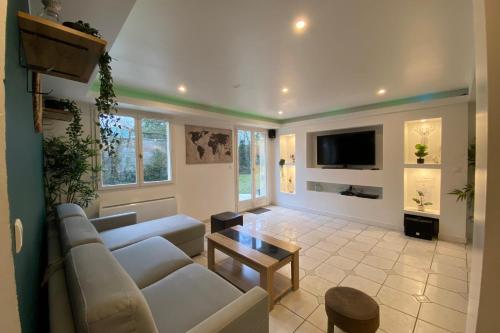 ein Wohnzimmer mit einem Sofa und einem TV in der Unterkunft Clos des chênes 14Pers near Disneyland & Paris table football darts in La Houssaye-en-Brie