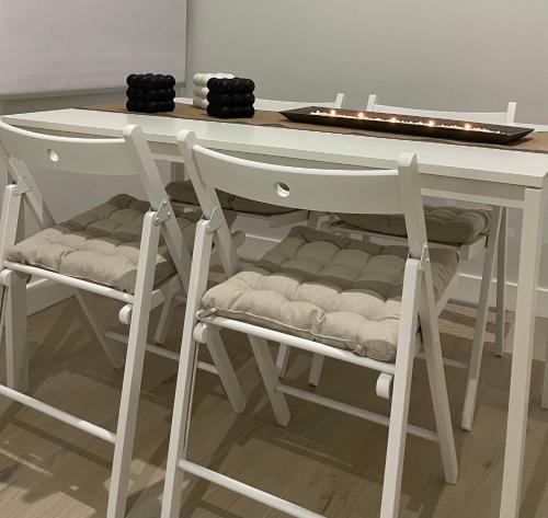mesa con 2 sillas, mesa blanca y taburete en Apartamentos Corredera 2, en Arcos de la Frontera