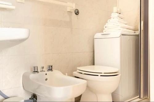 a white bathroom with a toilet and a sink at LA CALETTA HOME in Villanova di Ostuni