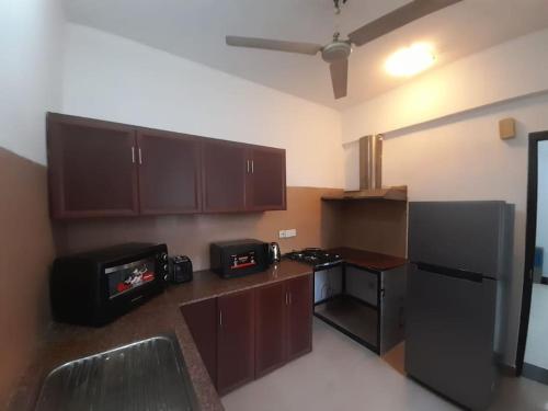 Golden Residencies - Colombo - 3 Bed Apartment في كولومبو: مطبخ بدولاب بني وثلاجة سوداء
