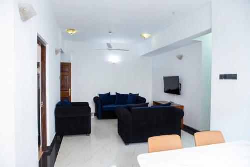 Golden Residencies - Colombo - 3 Bed Apartment في كولومبو: غرفة معيشة مع اثنين من الأرائك الزرقاء وتلفزيون