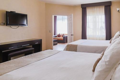 Habitación de hotel con 2 camas y TV de pantalla plana. en Hotel Real de San Jose, en Tequisquiapan
