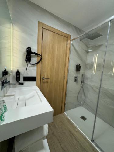 een badkamer met een witte wastafel en een douche bij Hotel Europa in Arteixo