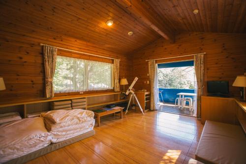 una sala de estar con una cama y una ventana en una cabaña en PICA Chichibu, en Chichibu