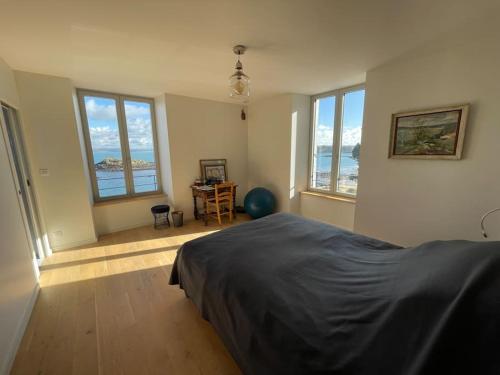 une chambre avec un lit, un bureau et des fenêtres dans l'établissement Ty Domovoï, vue mer, à Douarnenez