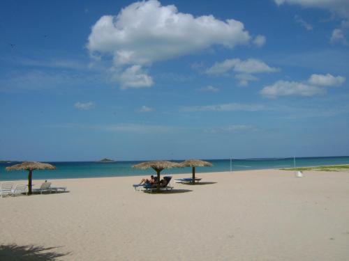 a group of people sitting under umbrellas on a beach at Pigeon Island Beach Resort and Spa in Nilaveli