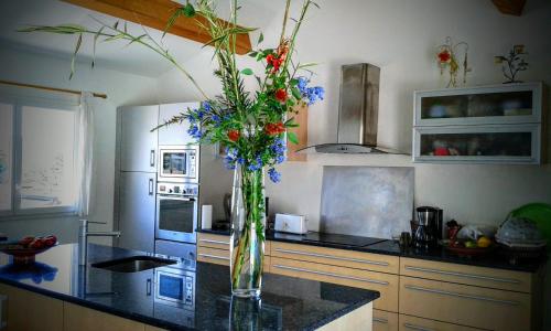 une cuisine avec un vase rempli de fleurs sur un comptoir dans l'établissement Casalta di san ghjuva, à Eccica-Suarella