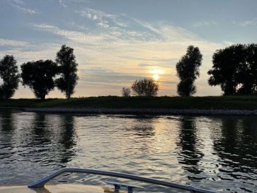 a boat on a river with the sun setting at Holiday home with motorboat in Olburgen
