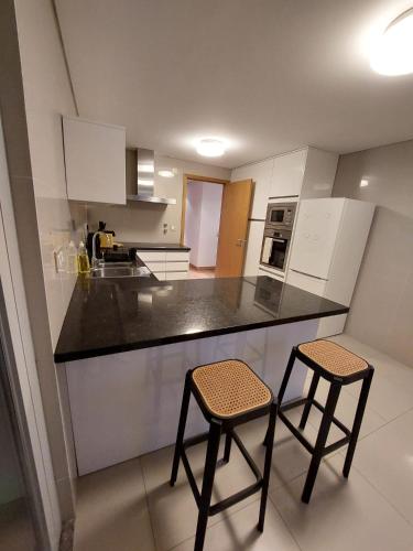 eine Küche mit zwei Hockern und einer schwarzen Arbeitsplatte in der Unterkunft Ramona in Aveiro