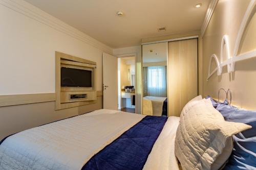 a bedroom with a bed and a flat screen tv at Flat Brasília 50m2 com varanda in Brasilia