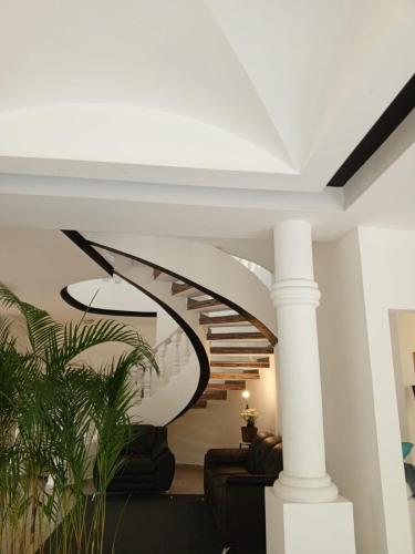 a spiral staircase in a living room with white ceilings at Habitación con balcón en una Mansión in Tegucigalpa