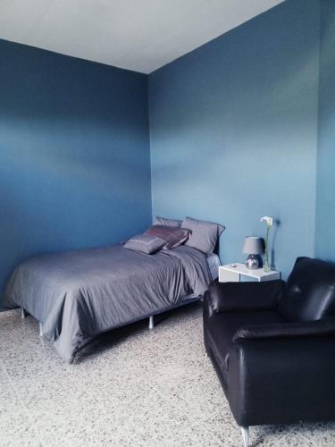 a blue bedroom with a bed and a chair at Habitación con balcón en una Mansión in Tegucigalpa