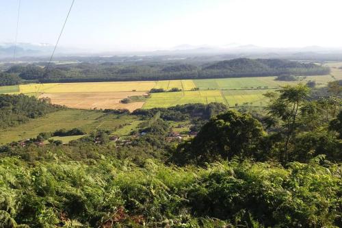a view from the top of a hill with fields and trees at casa do lago, paz e sossego. in Guaramirim