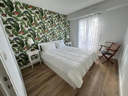 1 dormitorio con 1 cama con pared de flores en Ker Lafranec'h - Face Mer et Plage, 2 Chambres, WiFi, en Saint-Pierre-Quiberon