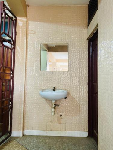 a bathroom with a sink and a mirror on a wall at Tuxedo Hotel in Accra