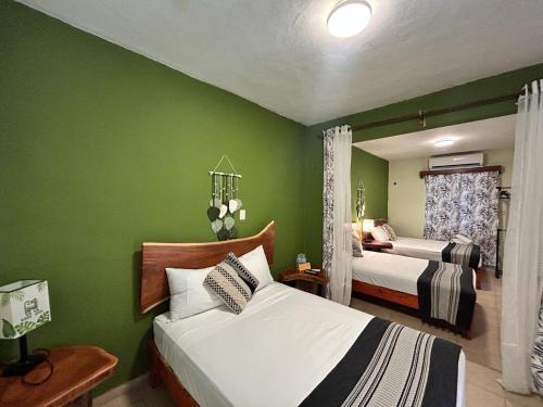 a bedroom with two beds and green walls at Hotel Koox Jool Bacalar in Bacalar