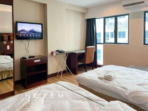 ein Hotelzimmer mit 2 Betten, einem Schreibtisch und einem TV in der Unterkunft SCSP 689 Premium SBR2B Near Imago and KKIA in Kota Kinabalu