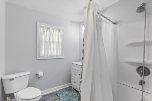 a white bathroom with a toilet and a shower at Sofia's Square Unit 3 in Omaha