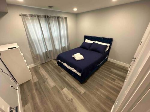 a bedroom with a bed with blue sheets and a window at The Comfy Suite - 1BR with Free Parking in Paterson