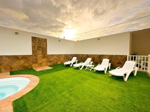 a room with chairs and a pool and grass at apartamento 1 tenerife sur in Arona