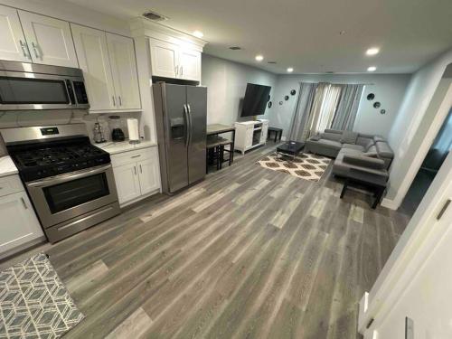 una cocina con armarios blancos y electrodomésticos de acero inoxidable en The Comfy Suite - 1BR with Free Parking, en Paterson