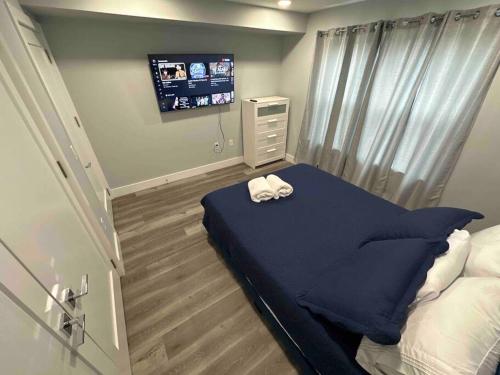 a bedroom with a bed with a blue blanket and a tv at The Comfy Suite - 1BR with Free Parking in Paterson
