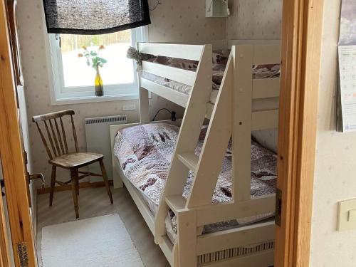 a room with two bunk beds and a chair at Holiday home SUNNE IV in Sunne