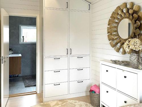 Holiday home UDDEVALLA XIX في Sundsandvik: غرفة نوم بها دواليب بيضاء ومرآة