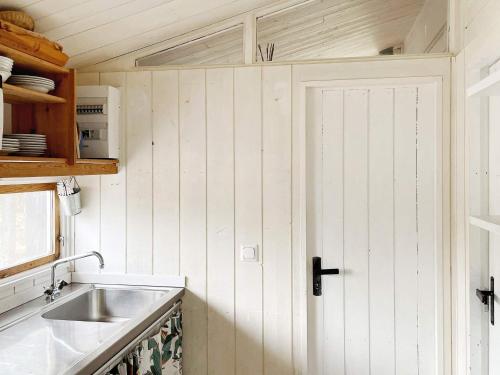 eine kleine Küche mit einem Waschbecken und einer Tür in der Unterkunft Holiday home GRISSLEHAMN XIV in Grisslehamn