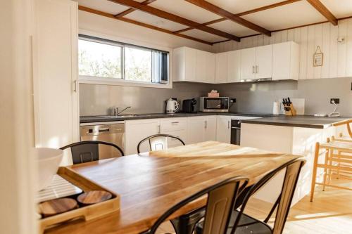 a kitchen with white cabinets and a wooden table at Bay Breeze - Boat - Bike - Hike in St Helens