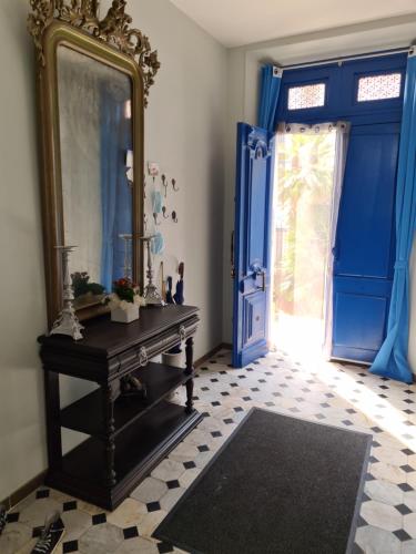 Cette chambre comprend un miroir, une table et des portes bleues. dans l'établissement LA MASCOTTE, à Vallauris