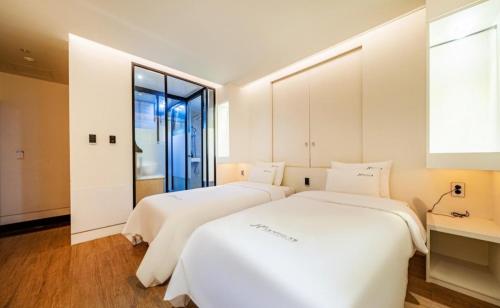 Duas camas brancas num quarto com uma janela em Noel Business Hotel em Busan