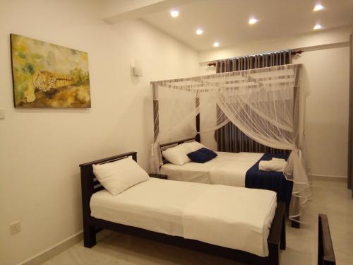 a bedroom with two beds and a painting on the wall at The Moose Weligama in Weligama
