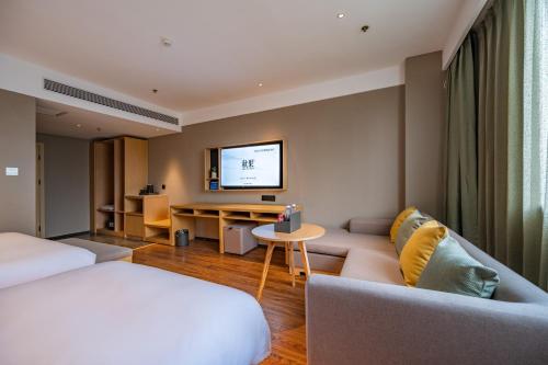 Cette chambre d'hôtel dispose d'un canapé et d'une télévision. dans l'établissement True Go Hotel - Beijing Asian Games Village National Convention Center, à Pékin