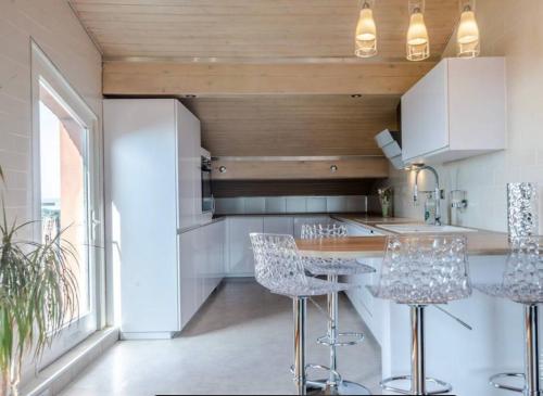 une cuisine avec des armoires blanches et des tabourets de bar dans l'établissement Le 7ème Ciel - 3 étoiles, à Thonon-les-Bains