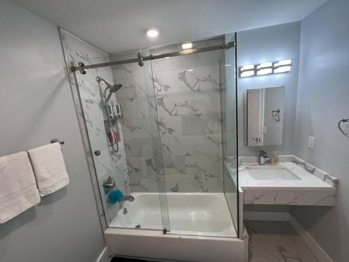 a bathroom with a glass shower and a sink at The Charming Suite - 1BR close to NYC in Paterson