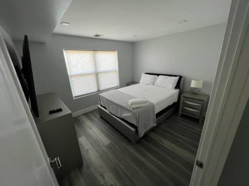 a white bedroom with a bed and a window at The Charming Suite - 1BR close to NYC in Paterson