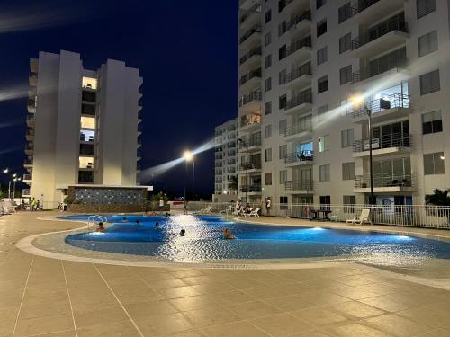 a swimming pool at night with two tall buildings at Aqualina Orange Girardot, décimo piso in Girardot