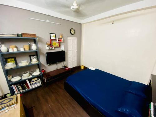 een slaapkamer met een blauw bed en een televisie bij Stay near Quest Mall & Don Bosco Park Circus in Calcutta