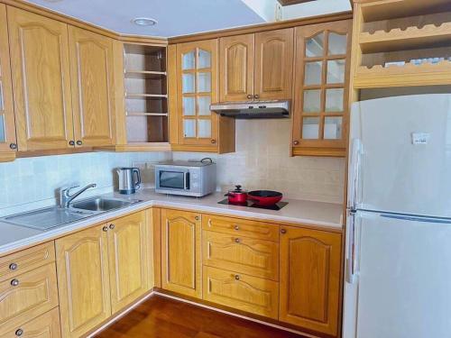 een keuken met houten kasten en een witte koelkast bij Happy Life Seaview @PalmPavillion in Hua Hin