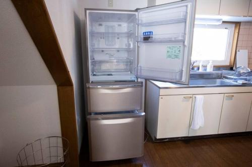 a kitchen with an open refrigerator and a sink at カムイ・スキーロッジ in Fukagawa