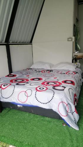 Una cama con un edredón rojo y blanco. en Cabaña Natura GREEN, en Líbano