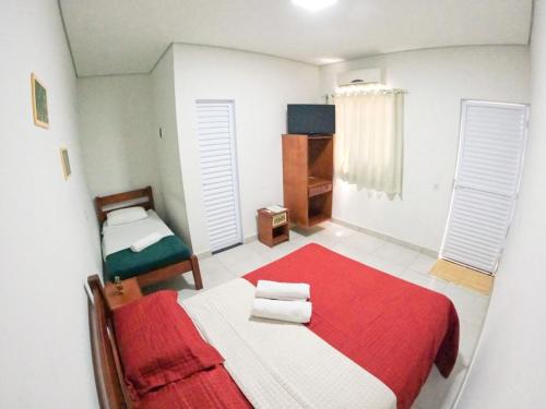 a bedroom with a red and white bed and a window at Baru Bonito - Suítes in Bonito